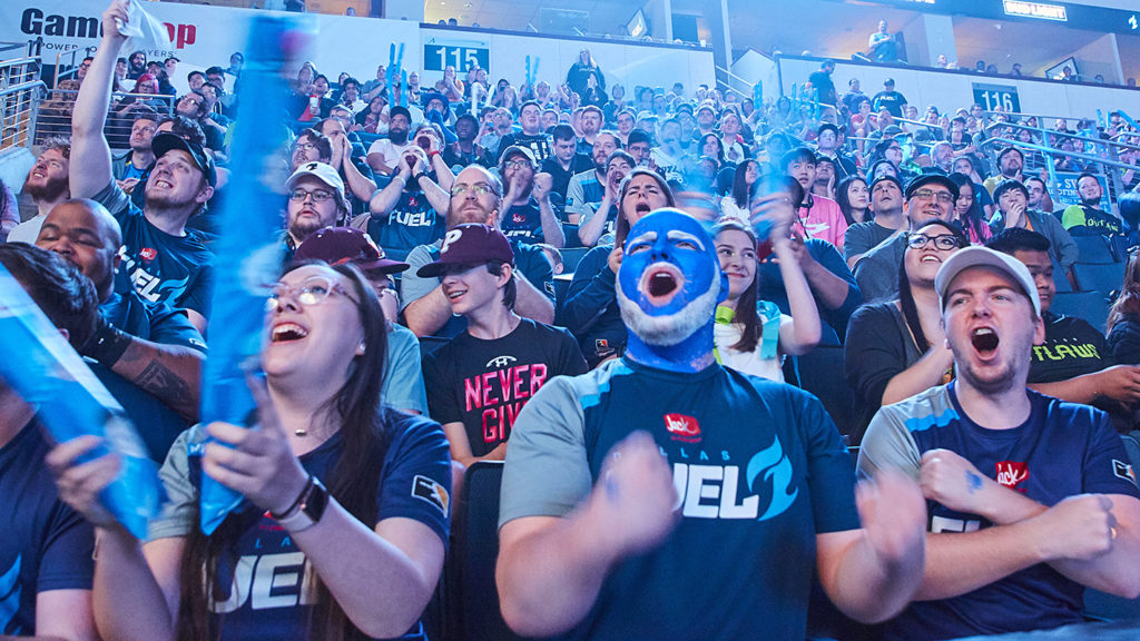 An image of Overwatch League fans at the venue. There's a guy with face-paint on and he looks awesome.