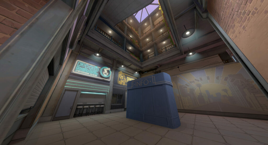 An info booth sits in the middle of an area on Sunset, VALORANT's new map, with a Sunset City mural, an unidentifiable shop, and a pho restaurant.