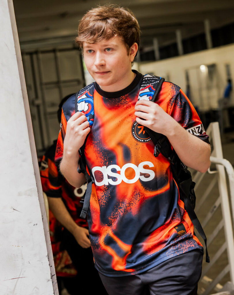 Fnatic coach mini wearing the jersey and holding a bag as he walks towards the Los Angeles Champs venue.