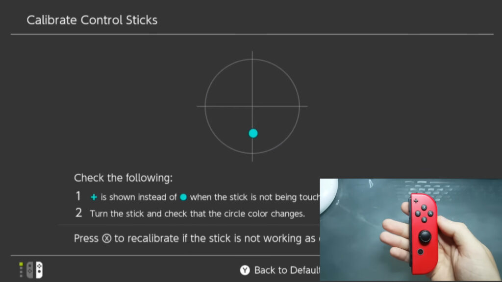 Shows a Nintendo Switch's Joy-Con controller being held without touching the joystick while the console's calibration tool detects a downward input.