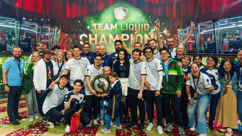 Team Liquid's Dota squad and staff stand and celebrate at The International 2024 with the Aegis of Champions.