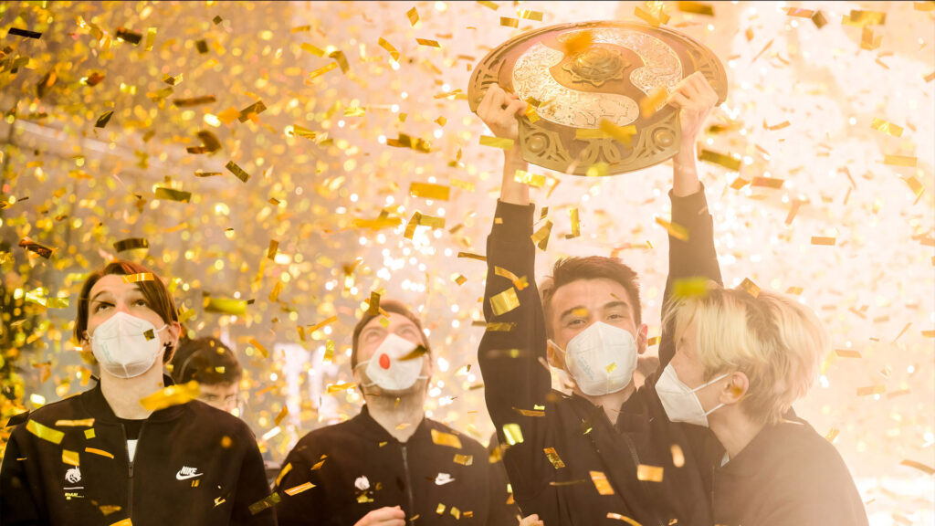 Team Spirit lift the Dota 2 trophy while wearing masks at TI 2021.