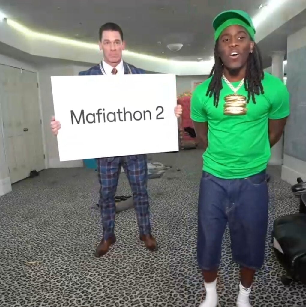 John Cena holds a board up next to Kai Cenat.