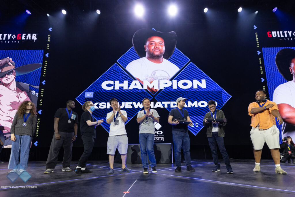 It's a photo of the top 8 players at the Guilty Gear Strive Evo 2025 tournament - people are on the stage.