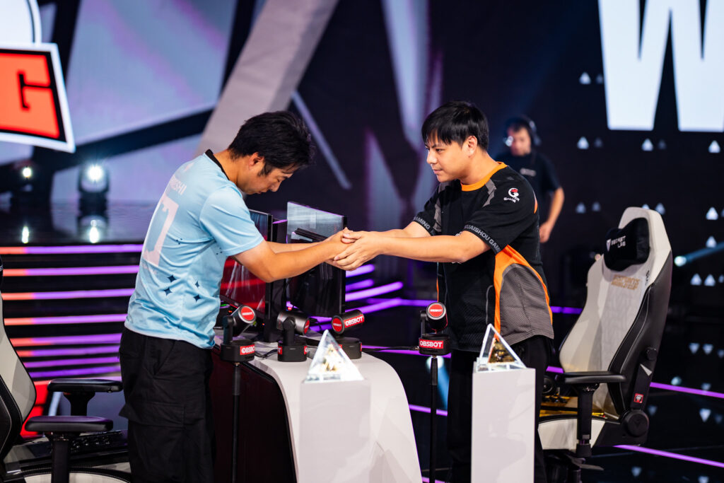 It’s a photo of two fighting games players Torimeshi and Xiaohai shaking hands before a match at the Street Fighter 6 Esports World Cup 2025.