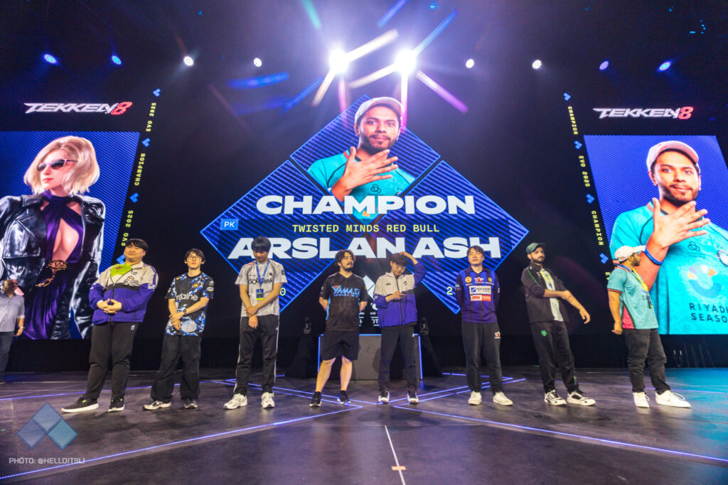 The photo features the top 8 TEKKEN esports players at the event Evo 2025: they are standing on the tournament stage.