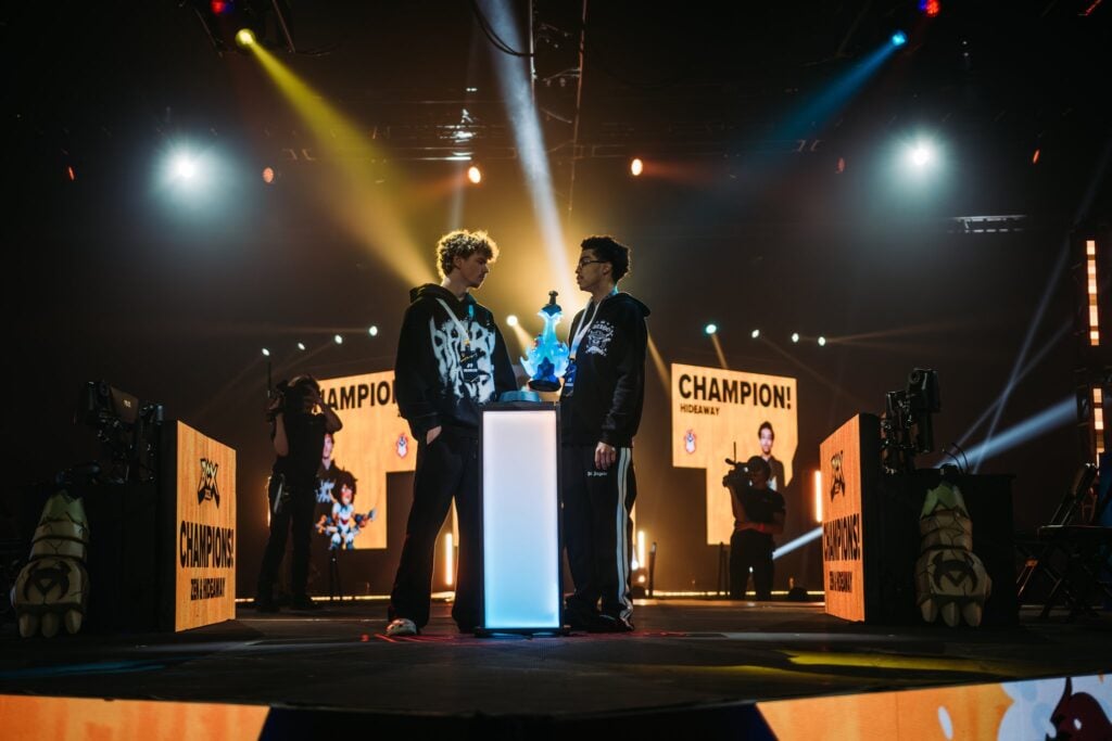The photo features Zen & Hideaway, the Brawlhalla 2025 Doubles World Champions - they are on the stage receiving the trophy.