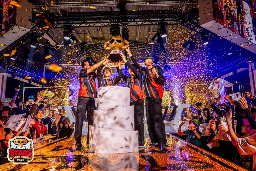 The photo features the Brawl Stars esports players from the team Crazy Racoon on the stage of the World Finals 2025, with the trophy, after winning the tournament.