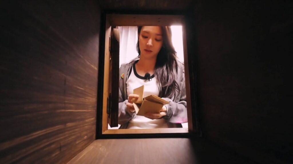 The screenshot from Single's Inferno Season 5 shows the female participant, Choi Mina Sue, taking out from a mailbox three postcards from men in episode 2.