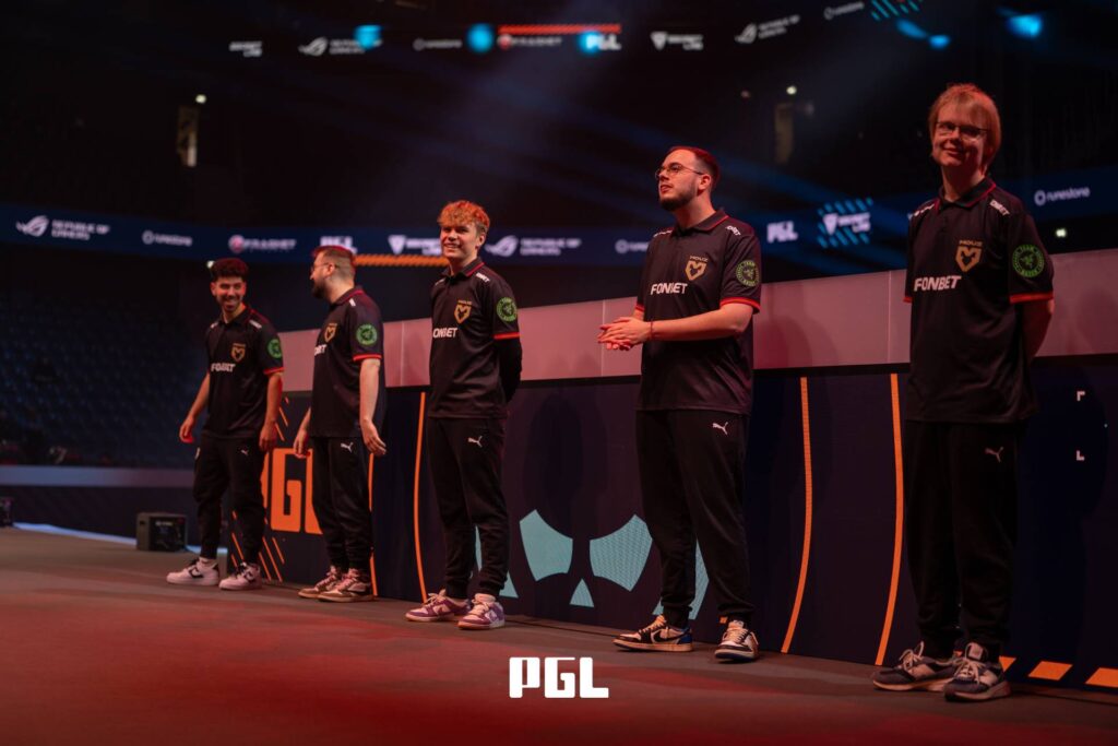It’s a photo of Counter-Strike 2 players from the team MOUZ during the Playoffs at the CS2 esports tournament PGL Cluj-Napoca 2026 — they stay on the stage before the third-place match versus The MongolZ.